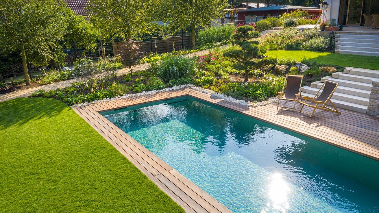 Woonzwembad van boven met groen gazon, helder blauw water op houten terras